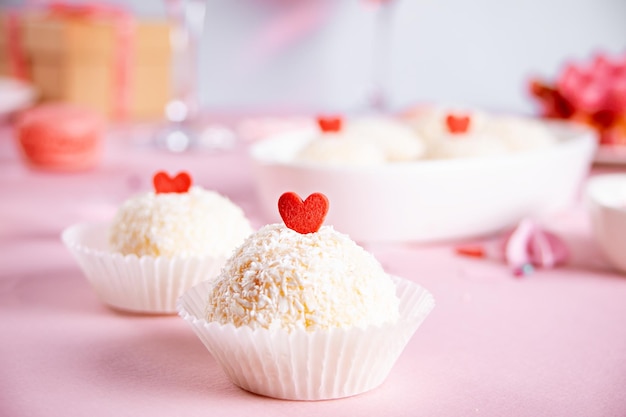 Bola dulce tradicional brasileña Brigadeiro hecha con leche condensada y copos de coco decorando con corazón de caramelo Día de San Valentín o concepto de día de la boda