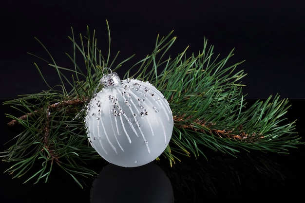Bola elegante branca no galho de árvore de natal em fundo preto