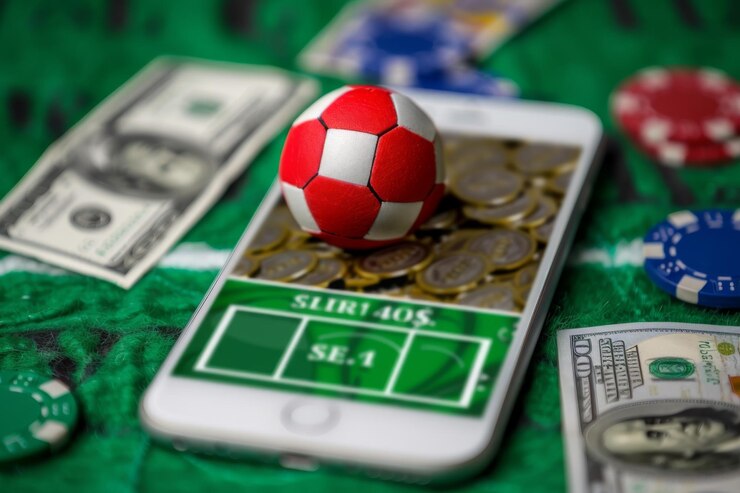 Bola de fútbol equilibrada en un teléfono inteligente con fichas de casino y billetes de dólar concepto de apuestas deportivas