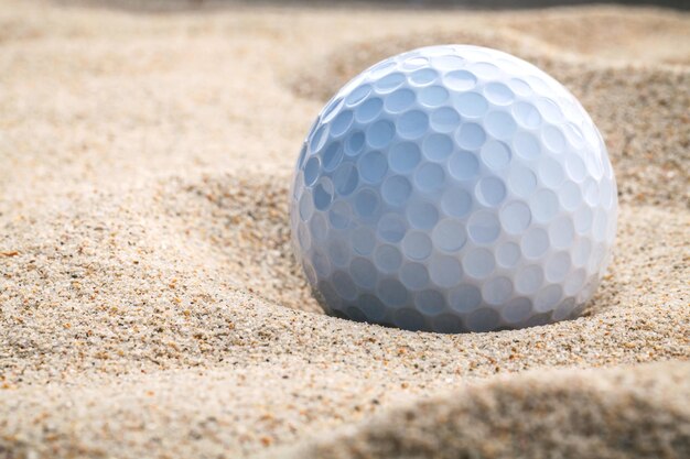 Bola de golf de cerca en un búnker de arena a poca profundidad de campo Una pelota de golf metida profundamente en una trampa de arena