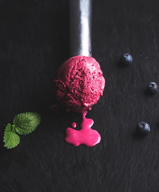 Bola de helado de arándanos de fusión sobre fondo de piedra pizarra negra