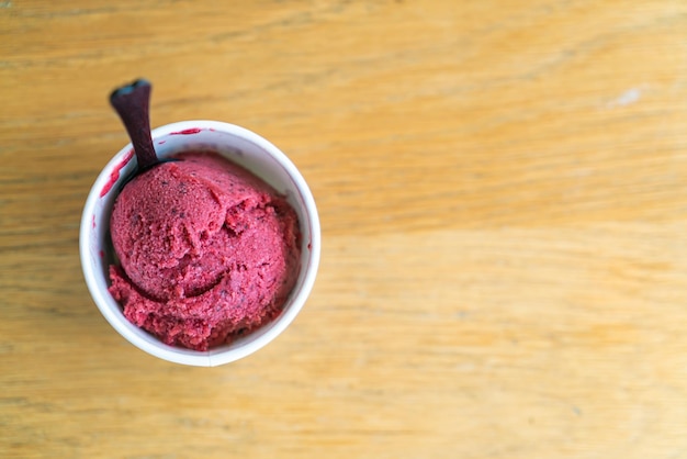 Bola de helado de bayas mixtas en taza sobre mesa de madera