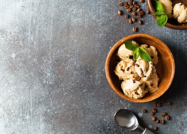 Bola de helado de café o chocolate en placa de madera con hoja de menta sobre fondo oscuro