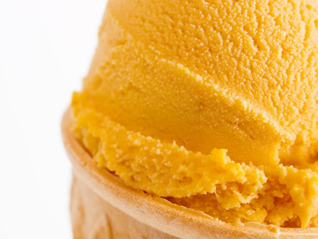 Bola de helado de calabaza gourmet en cono de pastel sobre fondo blanco.
