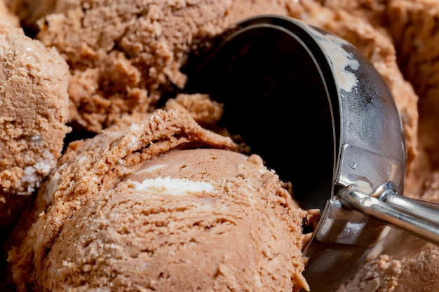 Una bola de helado de chocolate con una bola de helado de fondo.