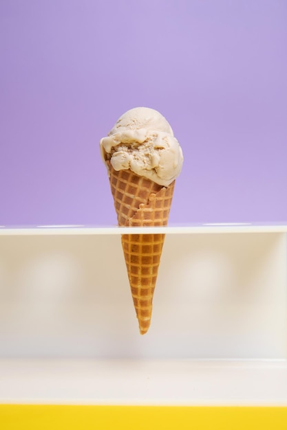 Una bola de helado en un cono de galleta sobre un fondo morado