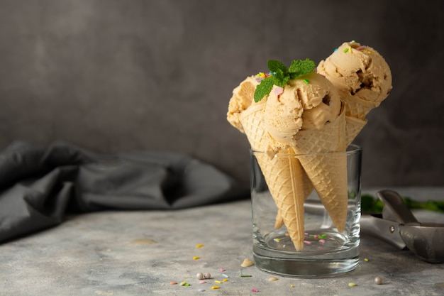Bola de helado en conos de waffles sobre fondo oscuro. Delicioso helado de verano. Copie el espacio.