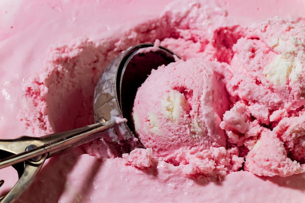 Una bola de helado de fresa con una cuchara dentro.