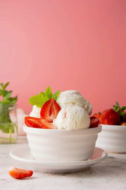 Bola de helado en un tazón con fresas frescas y menta. Deliciosa comida de verano, postre dulce.