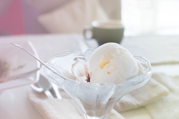 Bola de helado en un tazón de taza de plato transparente en una luz de fondo de café