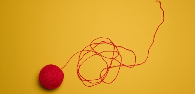 Foto una bola de hilos de lana roja sobre un fondo amarillo