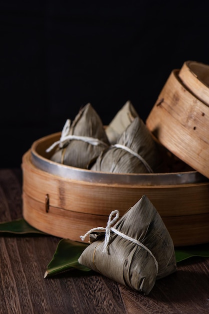 Bola de masa hervida de arroz Zongzi para el Festival del Bote del Dragón sobre fondo de mesa de madera oscura
