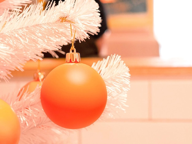 Bola naranja de Año Nuevo o Navidad en una rama artificial de un primer plano de abeto blanco