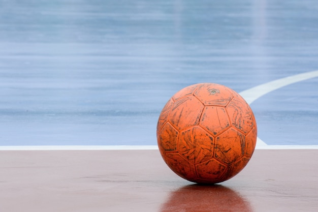 Bola naranja vieja y dañada en la cancha de fútbol sala