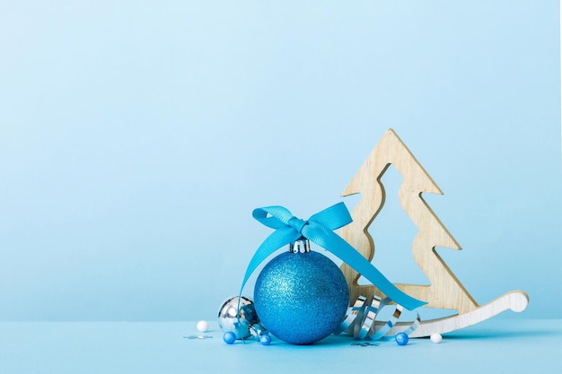 Bola de Navidad con árbol decorativo de madera sobre adorno de decoración de fondo de color con lazo de cinta con espacio de copia