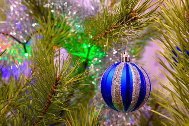 La bola de Navidad en un árbol de Navidad contra el fondo de luces borrosas de una guirnalda