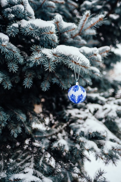 Bola de Navidad blanca azul en la rama de abeto de cerca