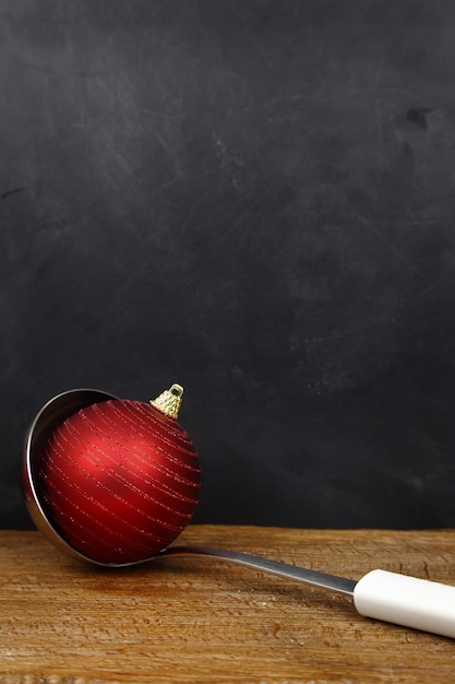 Bola de Navidad en una cuchara para servir y copie el espacio sobre fondo negro