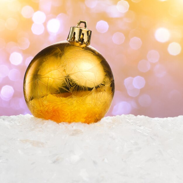 Bola de Navidad dorada sobre nieve sobre fondo festivo con espacio de copia