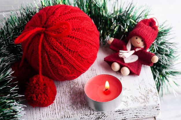 Bola de Navidad de punto rojo y decoración con vela encendida en interior escandinavo blanco. Copie el espacio para greting