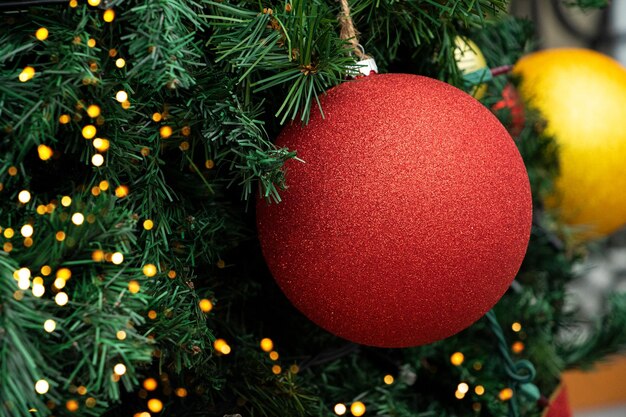 Bola de Navidad con purpurina roja en el abeto Bokeh brillante en la parte posterior