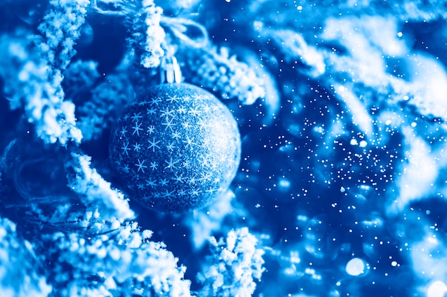 Bola de Navidad en una rama de árbol de Navidad cubierto de nieve sobre el fondo azul de invierno