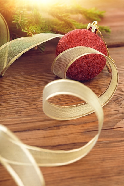 Bola de Navidad roja y cinta dorada en el fondo de una rama de árbol de Navidad