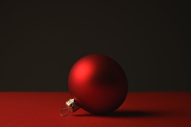 Bola de Navidad roja se encuentra contra un espacio oscuro. Foto de alta calidad