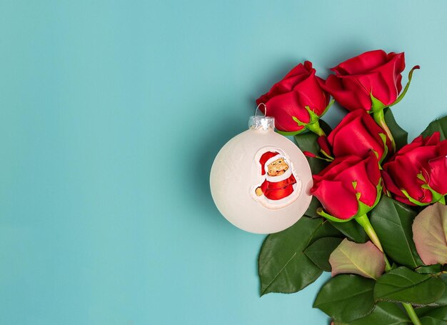 Bola de Navidad sobre rosas rojas y santa cerca