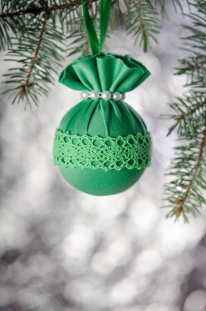Una bola de Navidad verde sobre una rama de abeto sobre un fondo plateado. Decoración de año nuevo.