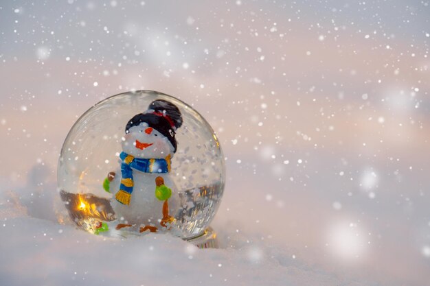 Foto bola de nieve de vidrio con muñeco de nieve en la nieve concepto de invierno tarjeta de año nuevo de navidad con espacio de copia bandera