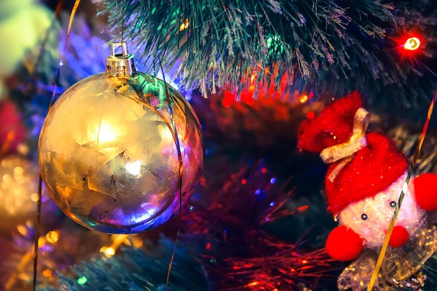 Bola de oro y juguete de punto en un árbol de navidad