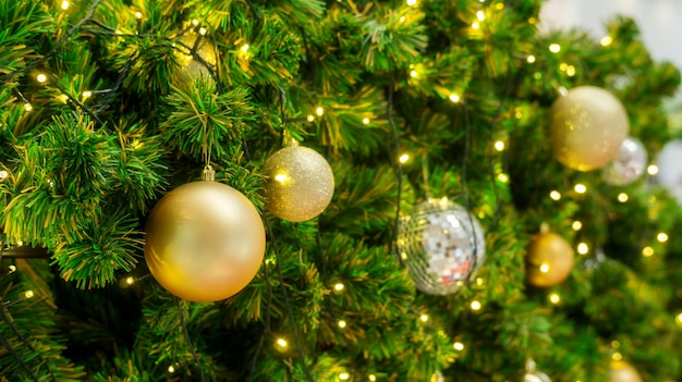 Bola de oro y plata colgando de un árbol de Navidad.