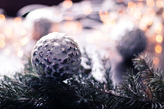 Bola de plata de navidad en la rama de un árbol de navidad con guirnalda efecto bokeh Foto Premium