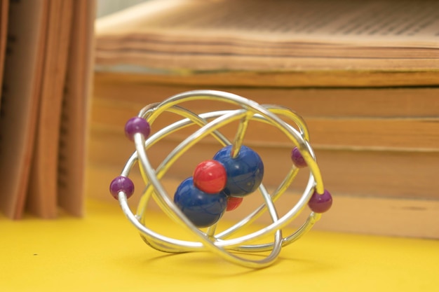 Una bola plateada con cuentas moradas y rojas se encuentra frente a una pila de libros.