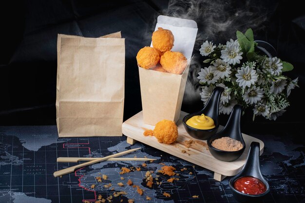 Foto bola de queso en recipiente de papel, caliente, ahumado, fondo negro