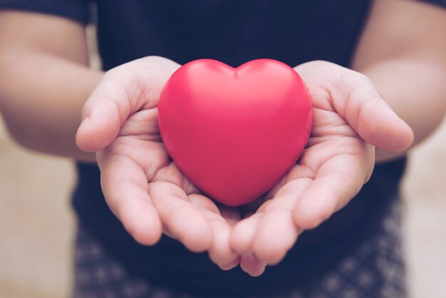 Bola roja del corazón: bola de espuma para aliviar el estrés, forma de corazón rojo en la mano de la mujer. Regalo de san valentin