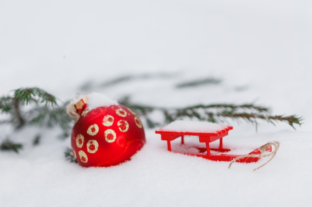 Bola roja de Navidad colgando de la rama de abeto cubierto de nieve