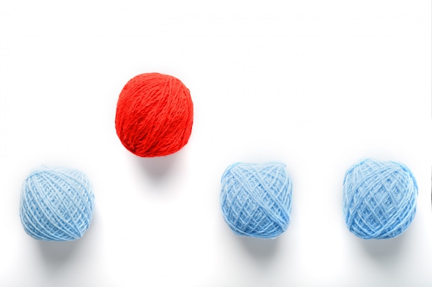Bola roja única salta de una fila de bolas de lana idénticas