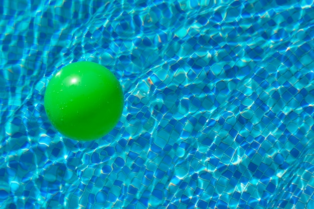 Bola verde redonda en la superficie del agua en una piscina con agua azul y olas El concepto de seguridad infantil cerca del agua