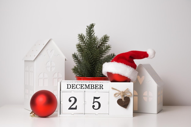 Bola vermelha de Natal com chapéu de Papai Noel no calendário com sacos de presentes datados de 25 de dezembro e árvore de Natal