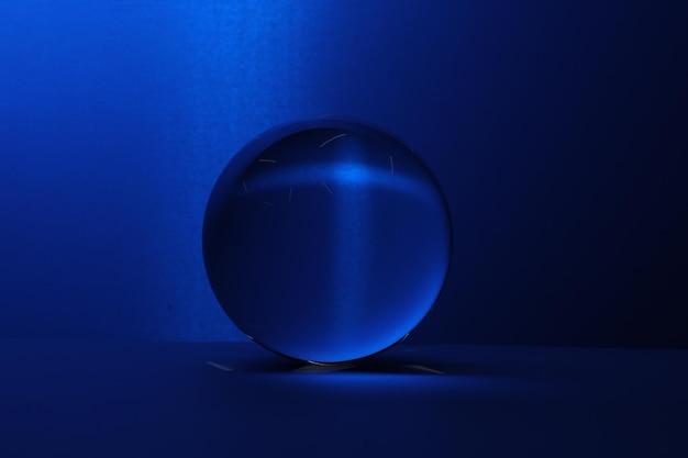 Bola de vidrio transparente en la mesa contra un fondo azul