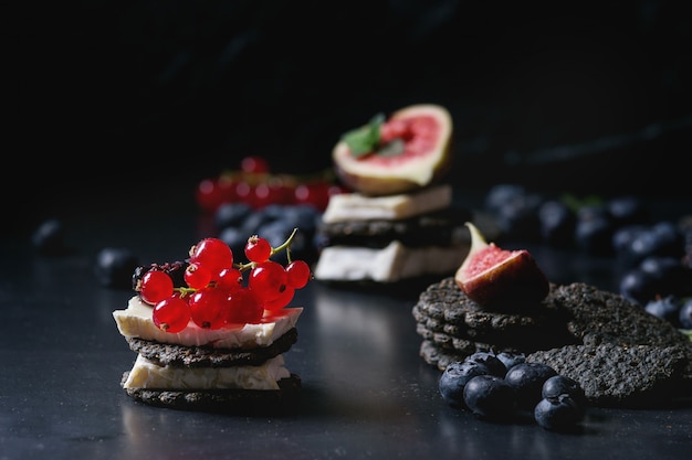 Bolachas pretas com queijo e frutas