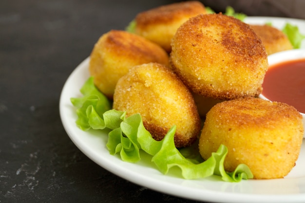 Foto bolas à milanesa de batata frita com molho de tomate