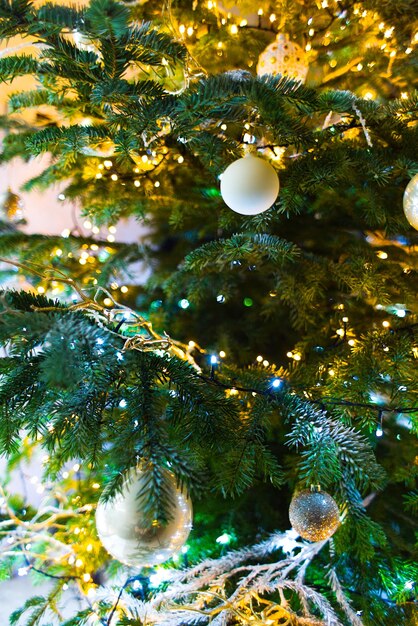 Foto las bolas adornan un árbol de navidad con luces parpadeantes en el fondo