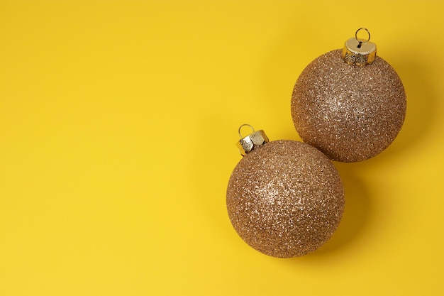 bolas de adorno de Navidad doradas sobre fondo amarillo con pino verde