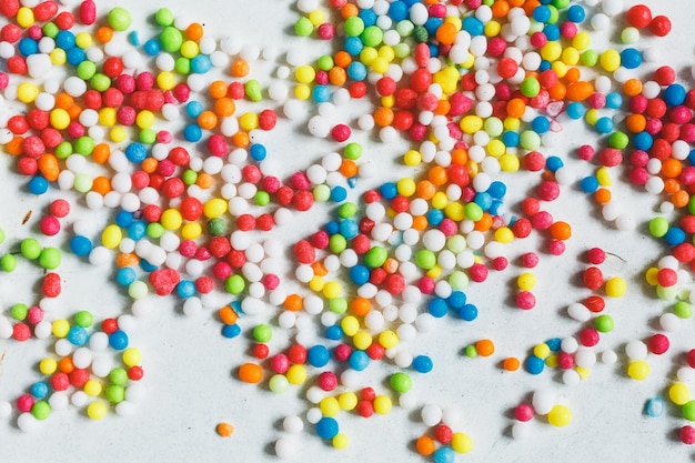 Foto bolas de azúcar de colores espolvoreadas sobre una vista superior de fondo blanco