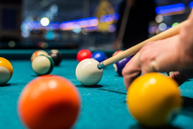 Bolas de billar en la mesa de billar con las manos y el palo del jugador El concepto de deportes y juegos de azar