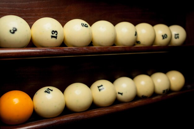 Bolas para billar pool en la estantería, bolas de billar para billar americano, bolas para billar ruso, bolas de colores o blancas para billar sobre un fondo de madera. Cerca de la foto. Enfoque suave.