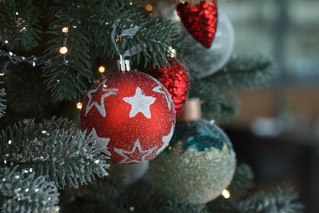 Bolas blancas y rojas de la Navidad del primer con una guirnalda de oro en ramas de árbol de navidad.